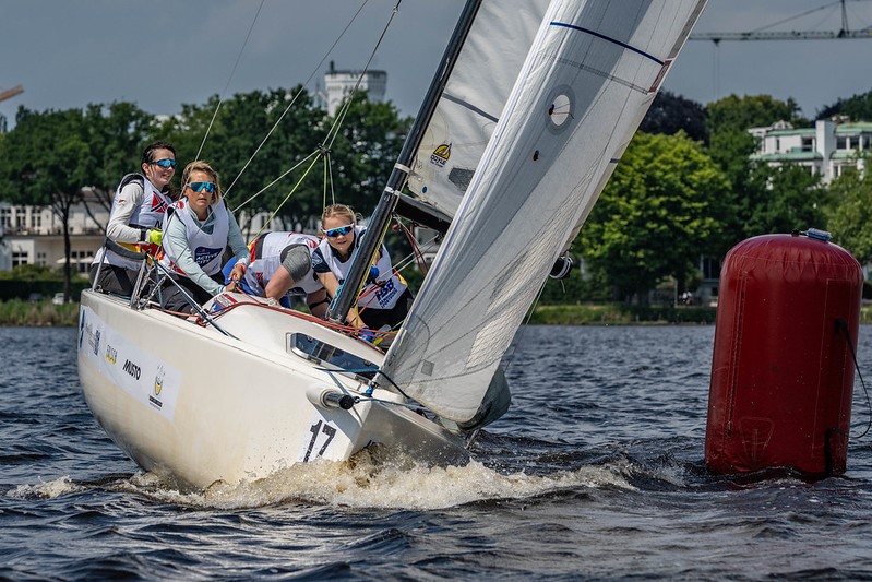 Vier Frauen segeln ein Segelboot bei Sonnenschein auf der Hamburger Außenalster.